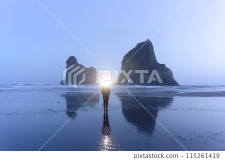Female tourist enjoying on Wharariki beach with iconic rocky mountain in archway island at New Zealand Female tourist enjoying on Wharariki beach with iconic rocky mountain in archway island at New Zealand 115261419
