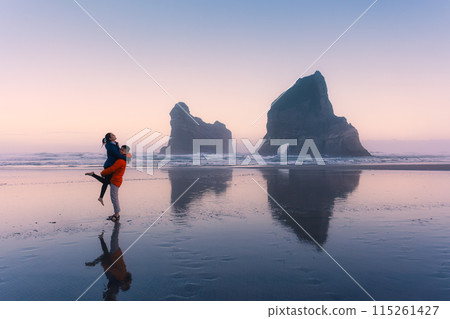Asian couple enjoying on Wharariki beach with iconic archway island at New Zealand 115261427