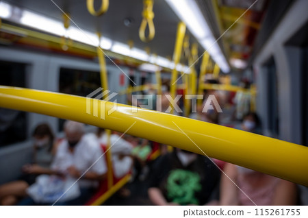 Vienna, Austria, August 2022. Shot with blurred conceptual image inside a subway car. The figures of the sitting people can be recognized, the yellow supports are highlighted. 115261755