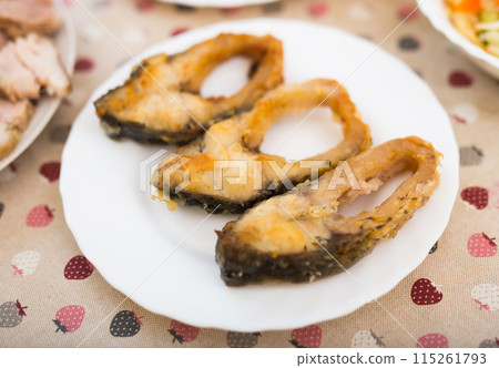 Pieces of the middle part of the carp baked on a white plate 115261793