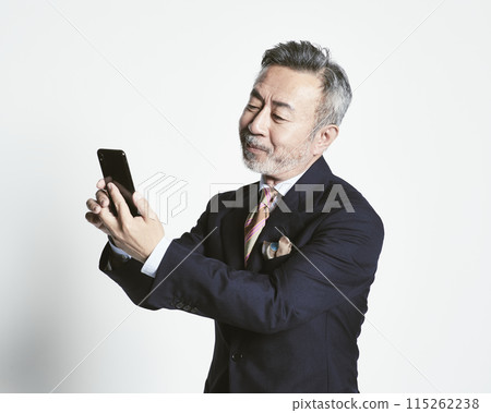 一名中年商人(上半身)拿著白色背景的智慧型手機 一名中年商人(上半身)拿著白色背景的智慧型手機 115262238
