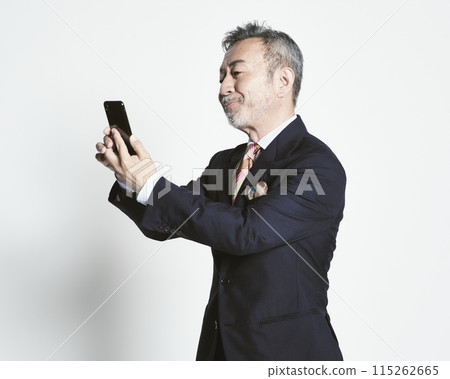 Middle-aged businessman holding a smartphone on a white background (upper body) 115262665