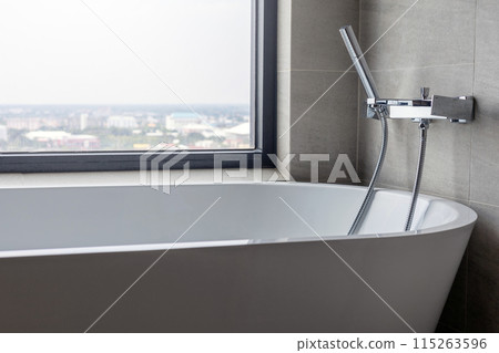 Modern bathroom interior with clean bathtub and shower and a spa-like window for natural light in luxurious home design 115263596