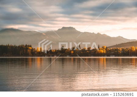 Scenery of sunrise over mountain range and autumn forest on Lake Wanaka Scenery of sunrise over mountain range and autumn forest on Lake Wanaka 115263691