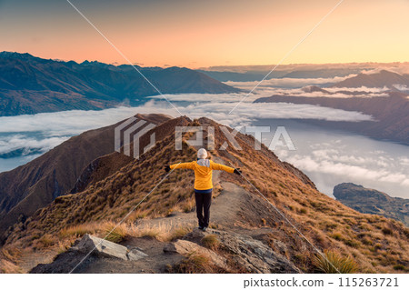 Asian hiker woman standing on the Roys Peak viewpoint with sunrise shine and fog on Wanaka at New Zealand Asian hiker woman standing on the Roys Peak viewpoint with sunrise shine and fog on Wanaka at New Zealand 115263721