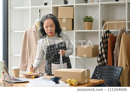 Middle age lady business owner working at her designer studio preparing parcel for shipping to customers Middle age lady business owner working at her designer studio preparing parcel for shipping to customers 115264606