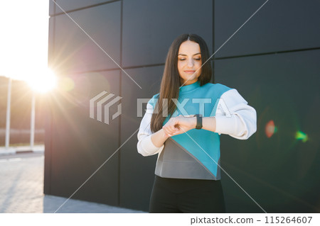 Woman uses a smart watch to measure the pulse on the hands. A woman does sports on the street. Fitness and a healthy lifestyle Woman uses a smart watch to measure the pulse on the hands. A woman does sports on the street. Fitness and a healthy lifestyle 115264607