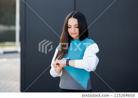 Woman uses a smart watch to measure the pulse on the hands. A woman does sports on the street. Fitness and a healthy lifestyle 115264608