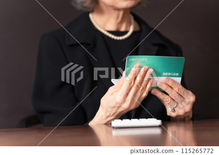 穿著喪服的老婦人看著她的銀行存摺，手裡孤獨 115265772
