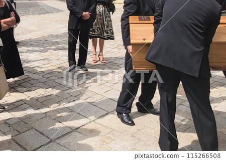 Men of funeral service loading the coffin into the hearse 115266508