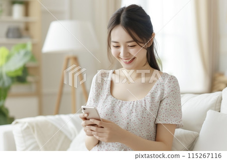 Young woman using a smartphone in the living room 115267116
