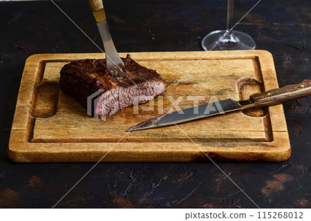 Roasted beef ribs with a glass of red wine presented on the table, traditional Argentine cuisine, Asado barbecue, Patagonia, Argentina. Roasted beef ribs with a glass of red wine presented on the table, traditional Argentine cuisine, Asado barbecue, Patagonia, Argentina. 115268012
