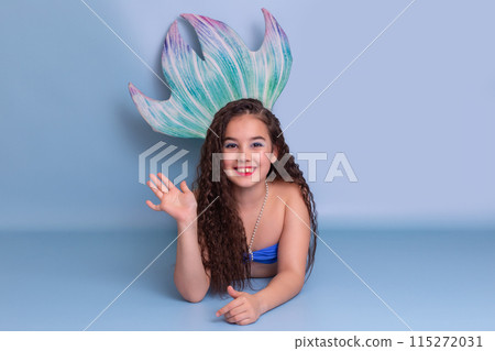 Cute girl in a mermaid costume, friendly, lies on a blue background 115272031