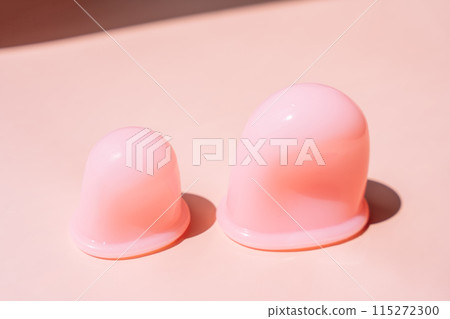 Pink silicone vacuum cups for anti-cellulite massage on a pink background 115272300