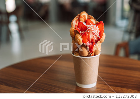 Bubble waffles in a cup with ice cream and strawberries Bubble waffles in a cup with ice cream and strawberries 115272308