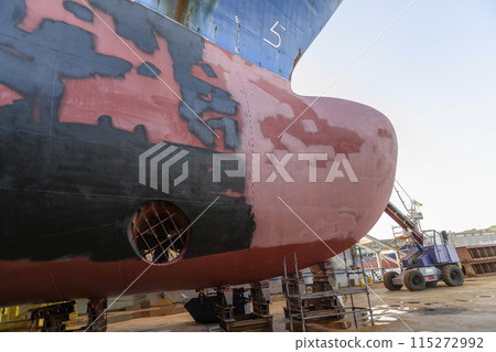 Cargo vessel in dry dock on ship repairing yard. Bulbous bow. 115272992