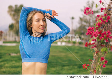 Young fitness woman in sports clothing stretching out in the park at sunny day. 115274348