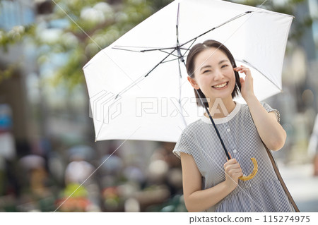 一位年輕女子撐著陽傘穿過城市 一位年輕女子撐著陽傘穿過城市 115274975
