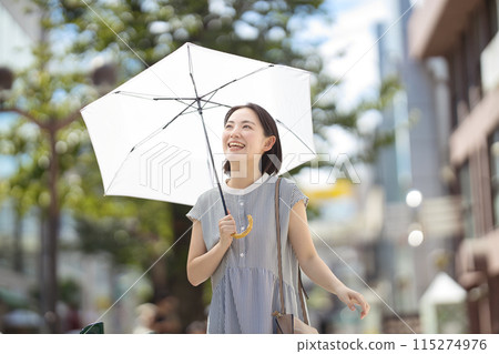 一位年輕女子撐著陽傘穿過城市 115274976