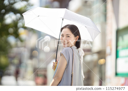 一位年輕女子撐著陽傘穿過城市 115274977