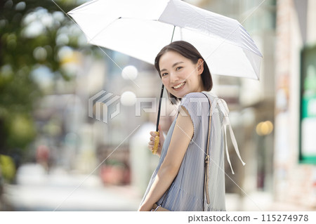 一位年輕女子撐著陽傘穿過城市 一位年輕女子撐著陽傘穿過城市 115274978