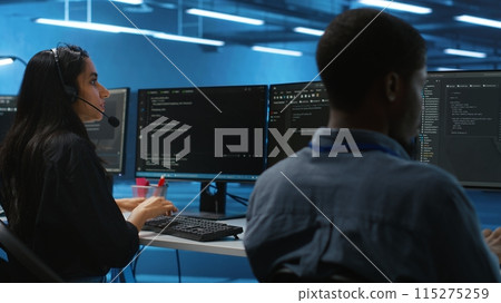 Woman talking in headphone mic, doing system analysis of server farm supercomputers. IT support worker in remote call using headset microphone in data center housing storage infrastructure Woman talking in headphone mic, doing system analysis of server farm supercomputers. IT support worker in remote call using headset microphone in data center housing storage infrastructure 115275259