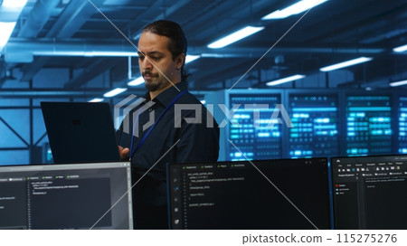 Manager overseeing server room, running code on laptop, troubleshooting and upgrading technologically advanced hardware clusters. System administrator programming in server farm 115275276