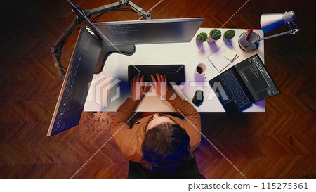 Top down view of remote worker typing code in personal office, using javascript language to develop software application. It specialist using multimonitor desktop setup to finish project, aerial shot 115275361