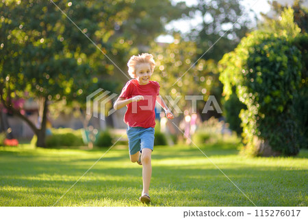 Elementary school child running on lawn in urban park on sunny day. Happy preteen boy having fun during walk. Outdoors activity for kids on summer holidays Elementary school child running on lawn in urban park on sunny day. Happy preteen boy having fun during walk. Outdoors activity for kids on summer holidays 115276017