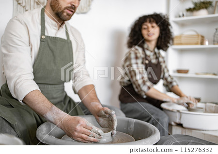 Man and woman potters working on pottery wheels in studio Man and woman potters working on pottery wheels in studio 115276332