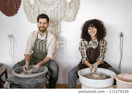 Man and woman potters working with clay on pottery wheels Man and woman potters working with clay on pottery wheels 115276336