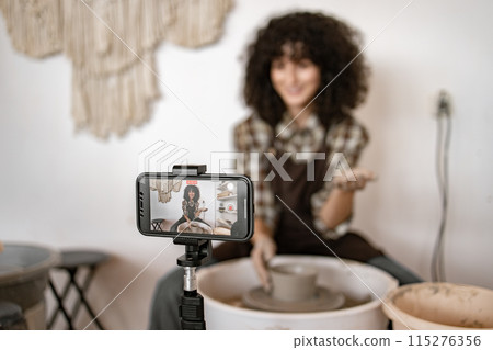 Young woman potter demonstrating pottery techniques for vlog Young woman potter demonstrating pottery techniques for vlog 115276356