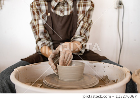 Female potter sculpting ceramic bowl on potter's wheel Female potter sculpting ceramic bowl on potter's wheel 115276367