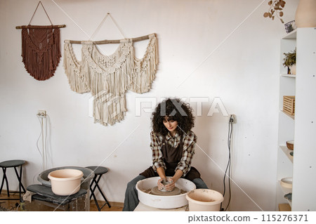 Female potter sculpts ceramic dish with potter's wheel in studio 115276371