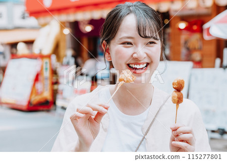 在大阪新世界吃著名炸串的年輕女子 115277801