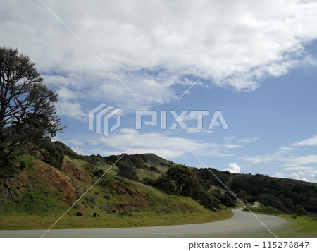 Plane soars above Angel Island hills with road leading to the top of 115278847