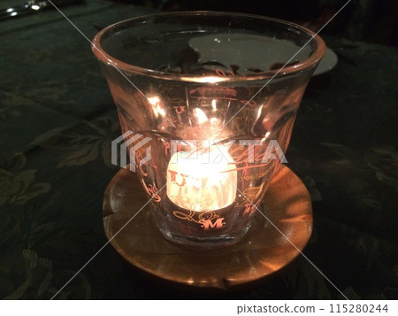 Candlelight flickering in a glass 115280244