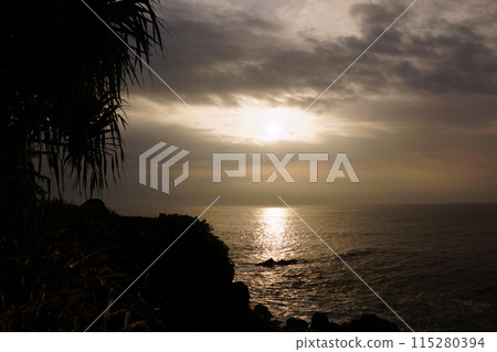 Sunrise over the ocean with waves crashing along rocky shore Sunrise over the ocean with waves crashing along rocky shore 115280394