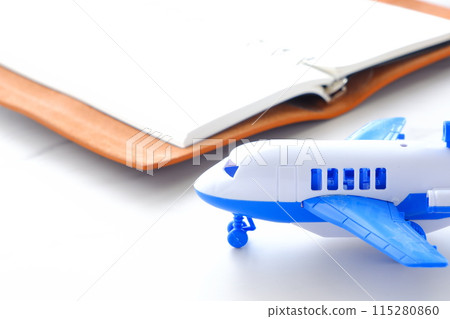一架客機等待起飛和一本打開的筆記本計劃旅行的圖像。 115280860