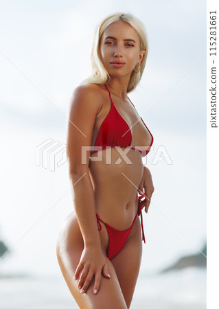 Tanned Blonde Fit Woman in Red Bikini on Beach 115281661