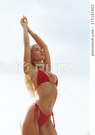 Blonde Fit Woman in Red Bikini Posing on Sunny Beach During Vacation 115281662