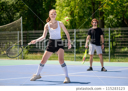 Happy young couple playing tennis in the park 115283123