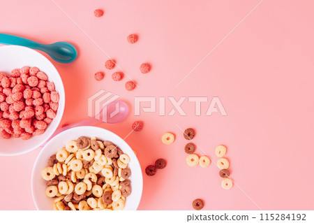 Corn rings without milk in white plates on a pink background with a blue spoon Corn rings without milk in white plates on a pink background with a blue spoon 115284192