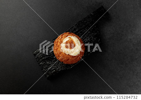 Classic Shu cake (choux). Custard dough based on butter and milk, classic custard filling with added cream on a black cutting board Classic Shu cake (choux). Custard dough based on butter and milk, classic custard filling with added cream on a black cutting board 115284732