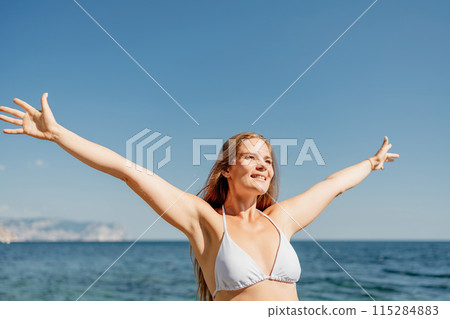 A woman in a bikini is smiling and waving at the camera 115284883