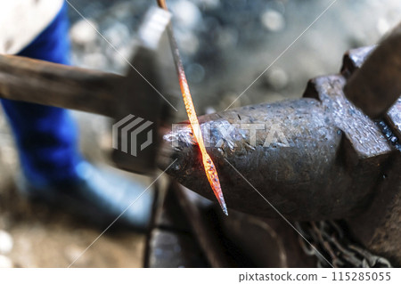 Blacksmith in a forge at work on an anvil. Hot metal forging 115285055