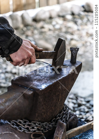 Blacksmith in a forge at work on an anvil. Hot metal forging 115285084