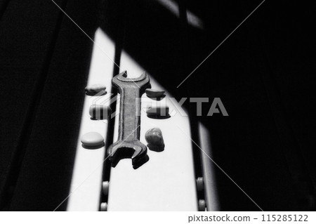 Old metal wrench on a workbench illuminated by the sun Old metal wrench on a workbench illuminated by the sun 115285122