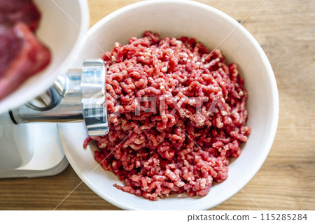Minced meat and electric meat grinder. Cooking beef minced in the kitchen with an electric grinder 115285284