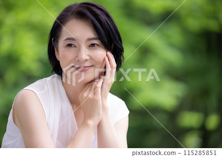 Beauty: Middle-aged woman smiling among fresh greenery Beauty: Middle-aged woman smiling among fresh greenery 115285851